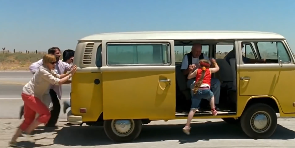 A família empurrando a clássica kombi amarela no filme Pequena Miss Sunshine, uma comédia dramática que ajuda no bem-estar emocional.