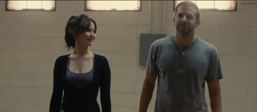Bradley Cooper e Jennifer Lawrence conversando no filme O Lado Bom da Vida, obra que retrata a saúde mental e os desafios da ansiedade.